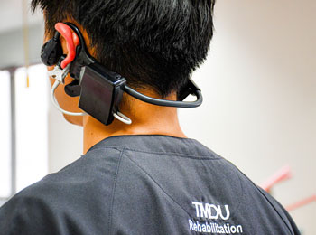 写真：ヘッドセット型ウェアラブルシステムの調整をする東京医科歯科大学リハビリテーション部の理学療法士