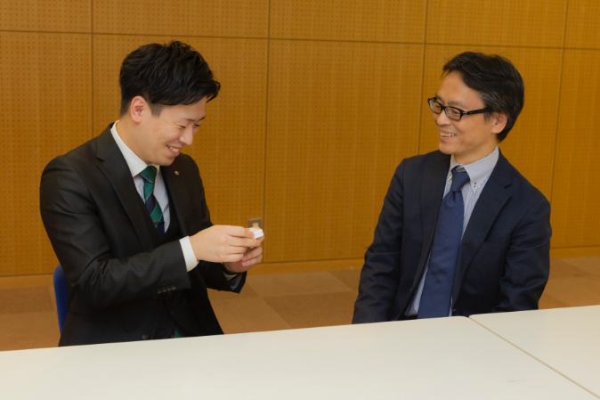 端末を持ち話し合う廣瀬氏と岩本氏。NTT西日本グループが企画・販売・提供し、株式会社ケイ・シー・シーがシステムの開発や運用を担う。