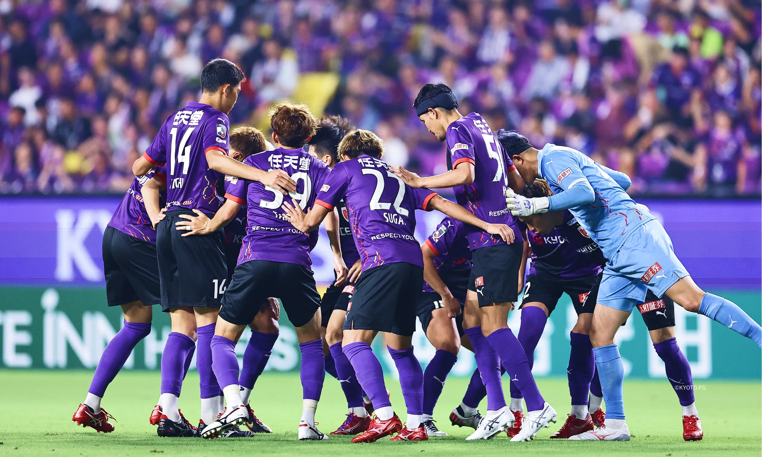 スタジアムで京都サンガF.C.の選手が円陣を組む写真